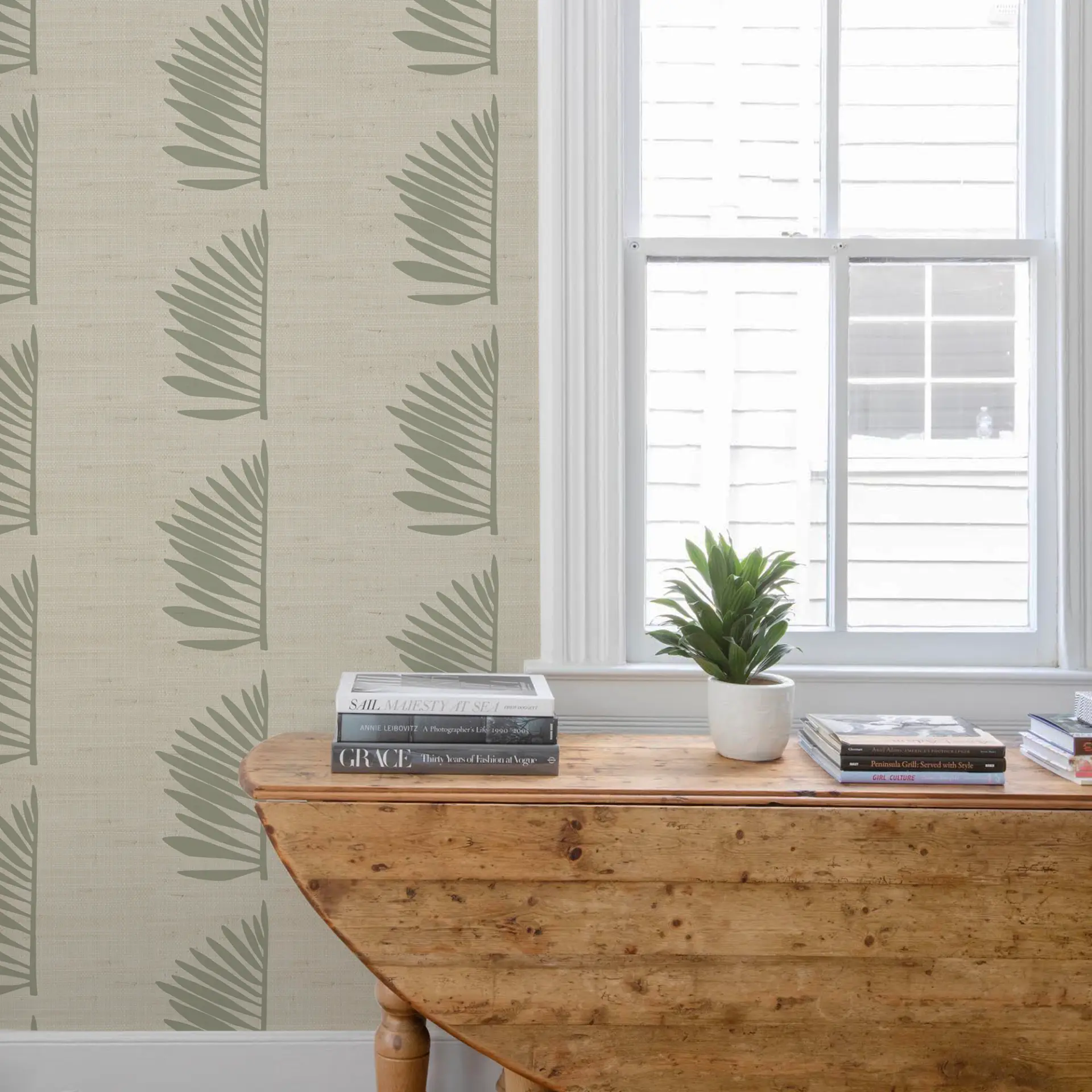Palmetto Grasscloth in Sage shown in a styled room with a wooden table and window.