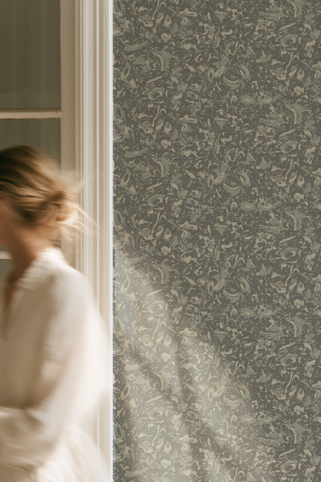 River Reef Grasscloth in Ocean on a wall beside a window, with a person passing in the foreground.