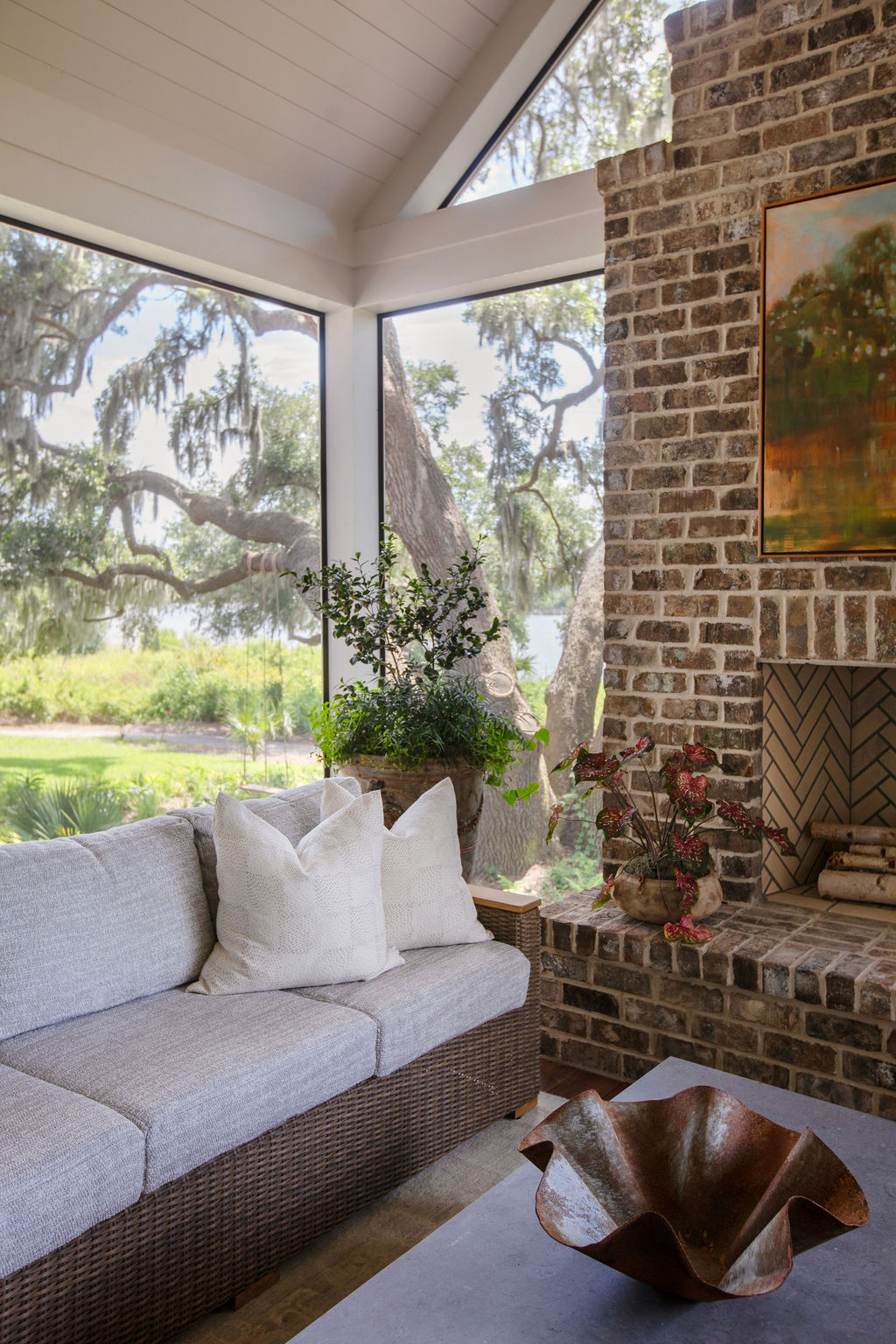A screened porch with woven chairs and a view of the garden